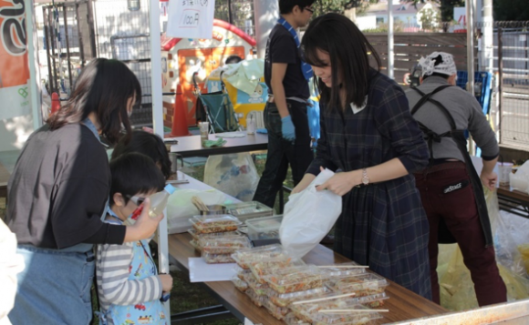 お客さんに品物を渡すワタミの江藤真見子さん（右女性）